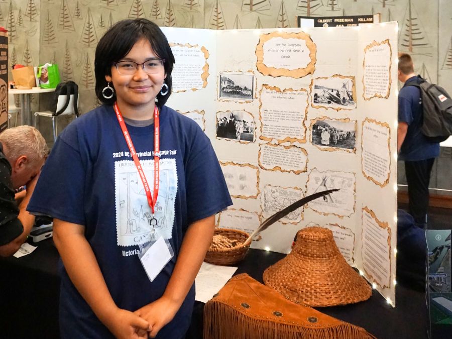 Student delegate at the 2024 Provincial Heritage Fair stands next to their project titled: How the Europeans affected the First Nations in Canada.