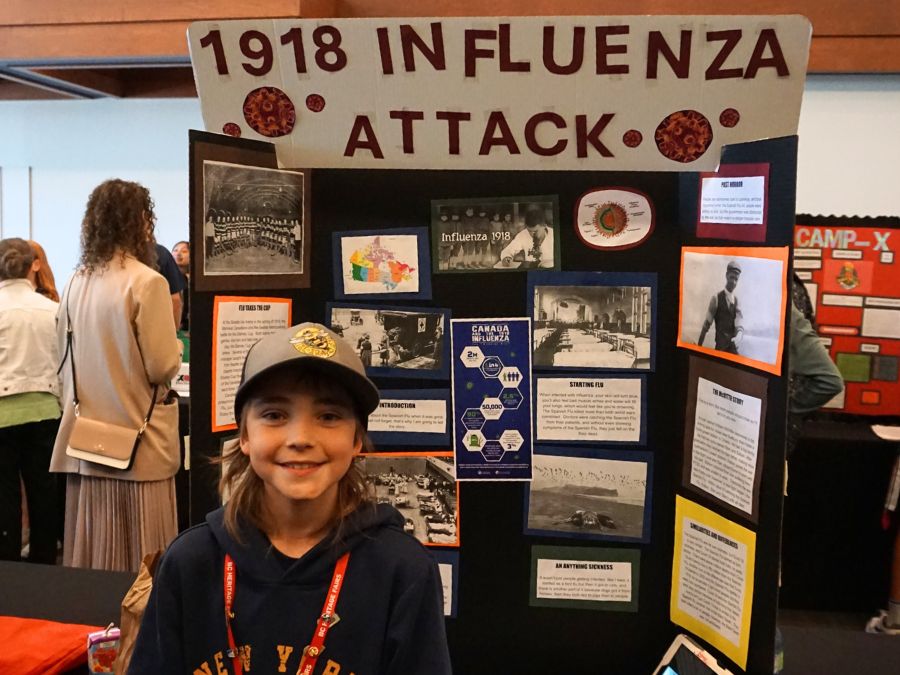 Student delegate at the 2024 Provincial Heritage Fair stands next to their project titled: 1918 Influenza Attack