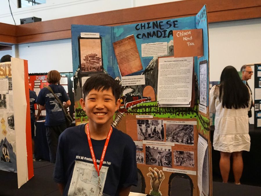 Student delegate at the 2024 Provincial Heritage Fair stands next to their project titled: Chinese Canadians.